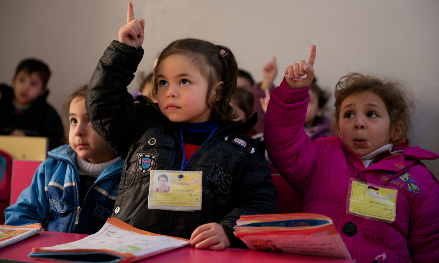 Eager to respond to their teacher, children raise their hands during an Arabic lesson at a kindergarten in Homs, Syria. © UNICEF/UNI156479/Noorani