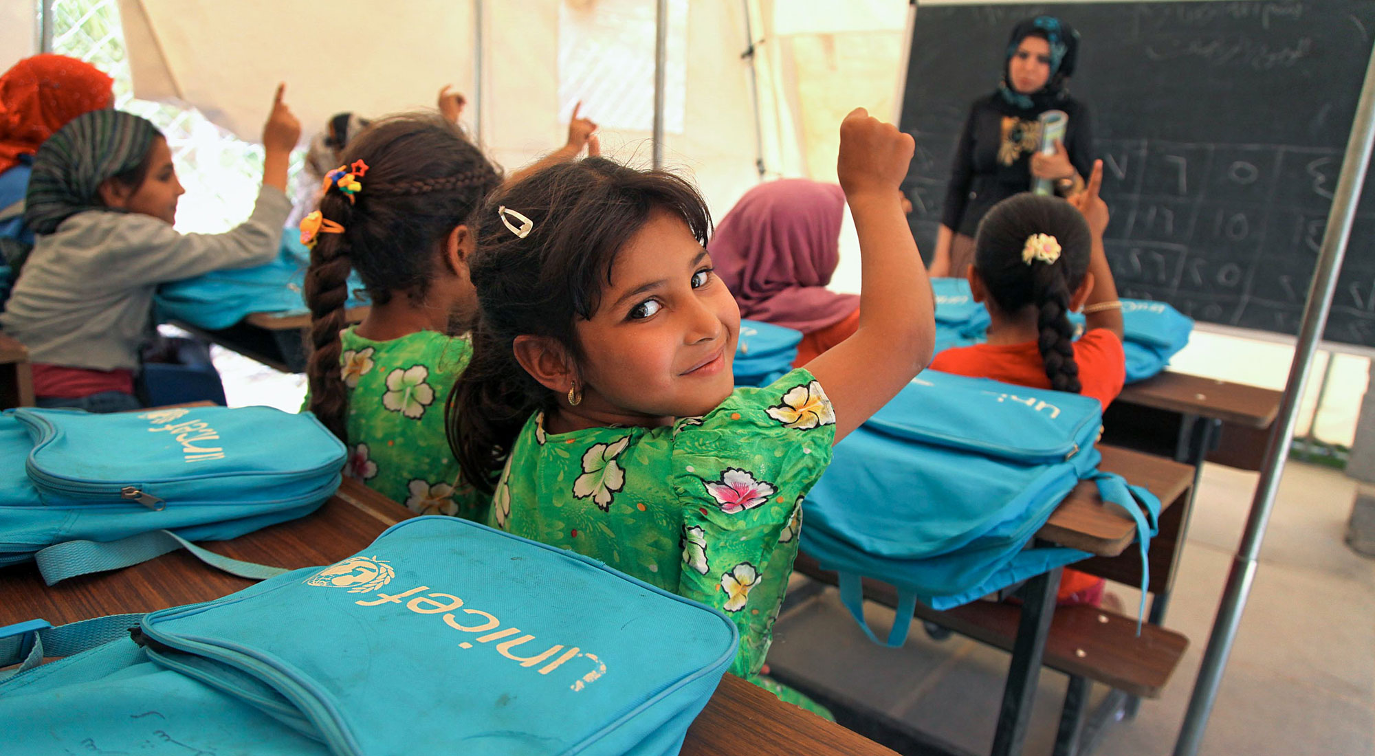 On 16 June a student raises her hand to answer a question from her teacher Hiba Ahmed in a tent classroom at the Al-Takya Al-Kaznazaniya school in Al-Takya Al-Kaznazaniya IDP camp, near Baghdad.