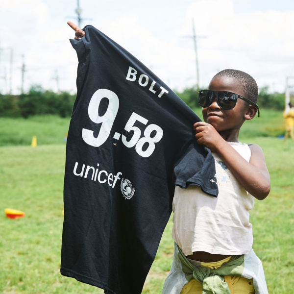 Six-year-old Catherine poses with Usain Bolt's Soccer Aid shirt and a pair of sunglasses at a Unicef-supported football academy in Nairobi, Kenya. Photo: Unicef/Burniston