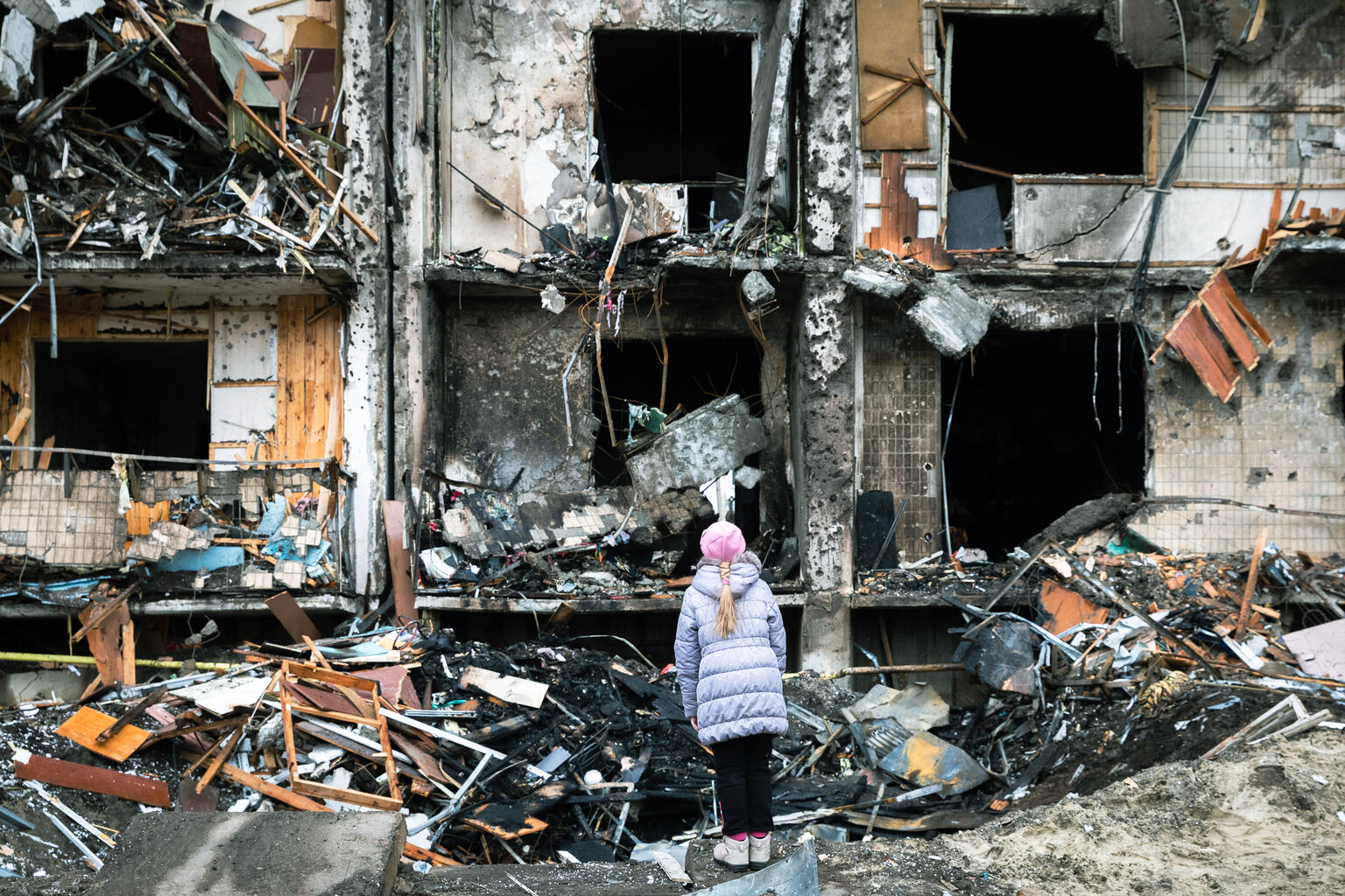 On 25 February 2022 in Kyiv, Ukraine, a girl looks at the crater left by an explosion in front of an apartment building which was heavily damaged during escalating conflict.